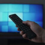 IPTV EPG troubleshooting: a remote pointed at a TV showing a programme guide grid